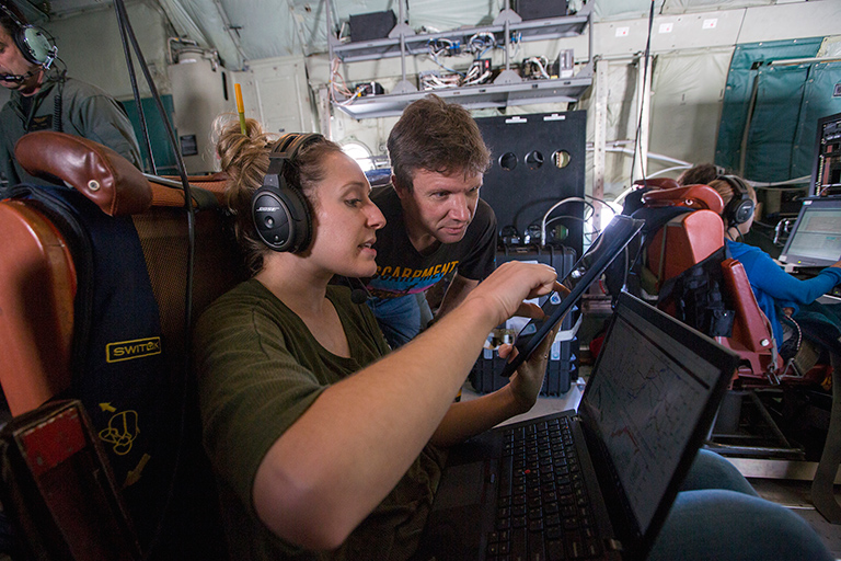 Researchers talk during a flight.