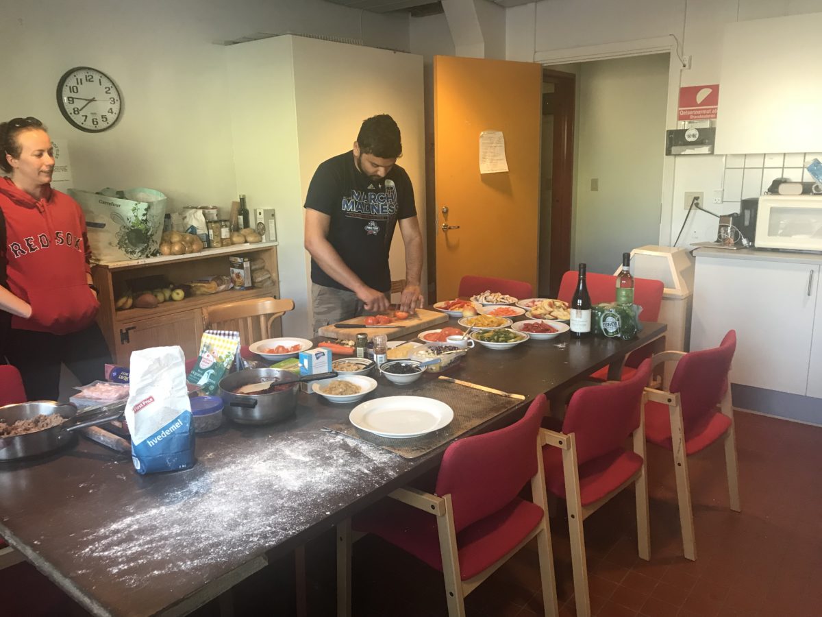 Photo of people gathering in a room to build their own pizza in Kanger, Greenland.